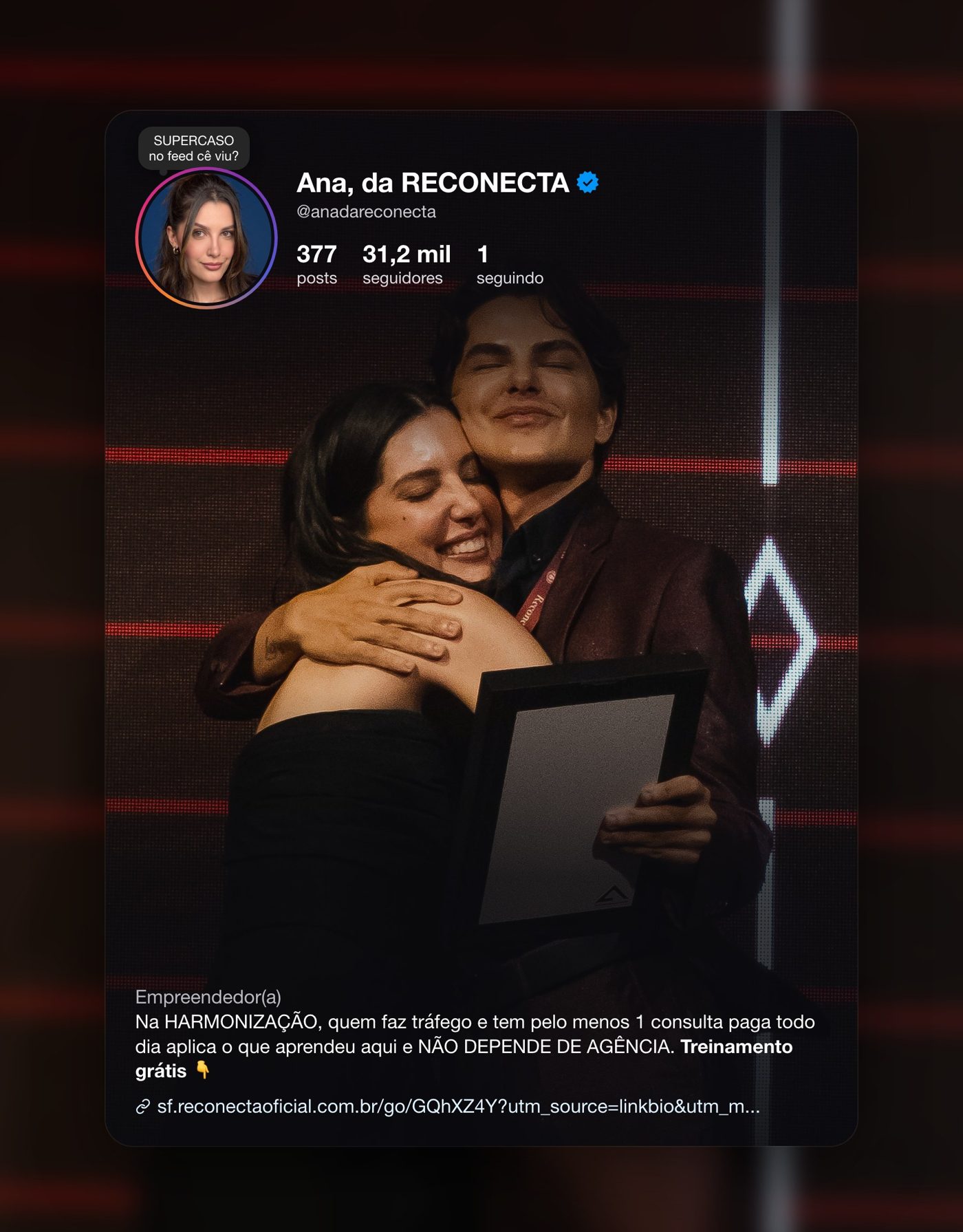 Ana Luiza abraçando uma mentorada no palco da premiação do evento da Reconecta, com card do perfil Instagram @anadareconecta sobreposto